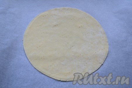 Охлаждённое тесто разделить на 7-9 частей. На столе, присыпанном мукой, каждую часть теста раскатать в лепёшку диаметром 14-15 сантиметров. Края каждой лепёшки обрезать, приложив к тесту крышку нужного диаметра. Противень застелить пергаментом и выложить на него лепёшку (у меня на противень помещаются сразу 2 таких лепёшки). Наколоть лепёшку из песочного теста вилкой (это нужно делать для того, чтобы тесто не вздувалось в процессе выпечки).