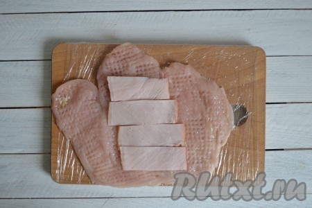 Ветчину нарезать тонкими ломтиками и выложить рядком по центру отбитого филе.
