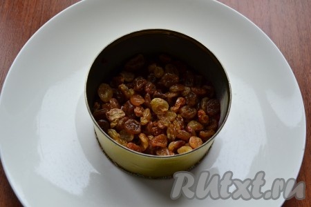 Вторым слоем выложить предварительно замоченный в кипятке на 10 минут, а затем отжатый изюм.
