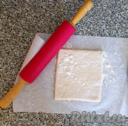 Тесто размораживаем при комнатной температуре, чтобы его можно было раскатать. Кладем тесто на бумагу для выпечки, присыпанную немного мукой. Тесто сверху также посыпаем мукой, чтобы оно не прилипало к скалке. Раскатываем скалкой прямоугольник толщиной 0,5 см. Перекладываем раскатанное тесто на стол, также немного посыпанный мукой. Бумага нам еще пригодится.
