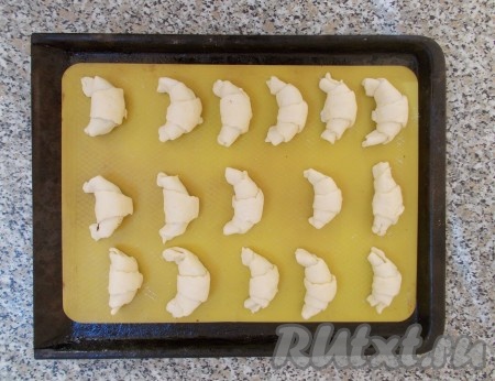 Каждый треугольничек скатываем и формируем рогалики, слегка изгибая концы в виде полумесяца. Укладываем рогалики на противень с силиконовым ковриком (очень удобно пользоваться этими ковриками, поскольку изделия при выпечке к нему не прилипают и нет необходимости дополнительно смазывать маслом, если у вас такого коврика нет – можете использовать бумагу для выпечки, но тогда смажьте её маслом). Пусть они так полежат 20 минут при комнатной температуре, чтобы согрелось тесто. Можно рогалики смазать перед выпечкой взбитым яйцом, а можно не смазывать - если готовые рогалики хотите посыпать сахарной пудрой. Но имейте ввиду, посыпать пудрой нужно обязательно горячие рогалики! Выпекать рогалики с маковой начинкой в разогретой духовке при температуре 180 градусов до золотистого цвета (примерно, 20 минут).
