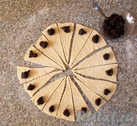 Берём маковую начинку. Я использую уже готовую маковую начинку с апельсином ТМ SantaVita Bakers - это намного упрощает и ускоряет процесс приготовления. Готовая начинка по форме напоминает небольшую «колбаску», делаем у её основания надрез (примерно, 1-1,5 см) и выдавливаем из неё маковую начинку с кусочками апельсиновой цедры в вазочку. Очень приятно пахнет апельсином. Не удержалась, попробовала её так - оказалась очень ароматной и вкусной, даже без выпечки. Чайной ложкой выкладываем маковую начинку на широкую сторону каждого получившегося треугольничка.