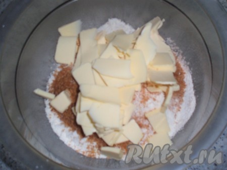В получившуюся смесь сухих ингредиентов добавить остывшие овсяные хлопья и нарезанное кусочками сливочное масло.
