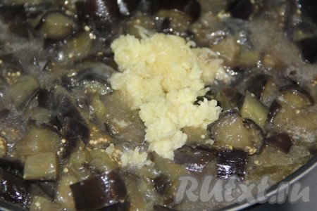 Добавить чеснок в сковороду к баклажанам и хорошо перемешать.