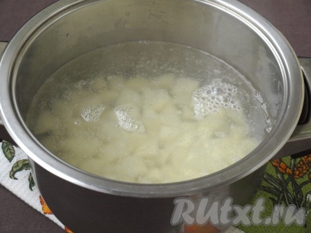 1,5 литра воды налить в кастрюлю и поставить на огонь. Когда вода закипит, добавить в неё нарезанный кубиками очищенный картофель, снять пену и варить 5 минут на небольшом огне.
