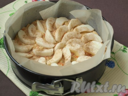 Форму диаметром 20-22 см застелить пергаментом и переложить в неё тесто. Оставшиеся яблоки нарезать ломтиками и разложить на поверхности, слегка вдавливая в тесто.
