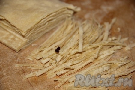 Таким образом раскатываем всё тесто в коржи, подсушиваем их по очереди на сухой сковороде и даём остыть. Затем коржи теста складываем стопочкой и тонко нарезаем. Для примера положила рядом спичку (см. фото). Полученного количества домашней лапши хватит на 2-3 супа, в зависимости от кастрюли. Оставшуюся лапшу можно подсушить до конца (оставив на сутки, разложенной на бумаге), хранить в целлофановом пакете.
