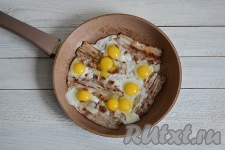 Не убирая бекон со сковороды, вбить яйца. Сковороду крышкой накрывать не нужно. Яичницу с беконом и&nbsp;перепелиными яйцами готовить на среднем огне 2-3 минуты, с куриными яйцами - 3-4 минуты.
