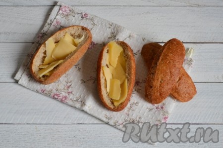 Сыр нарезать небольшими тонкими ломтиками или натереть на терке и выложить внутрь булок, из которых удалили мякоть.
