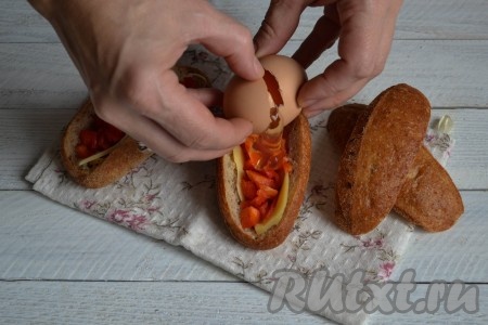 Поверх перца в каждую булочку выложить по одному куриному яйцу.
