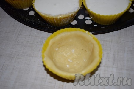 Кусочки теста обмакнуть в муку и распределить внутри формочек так, чтобы они полностью прилегали ко дну и стенкам.
