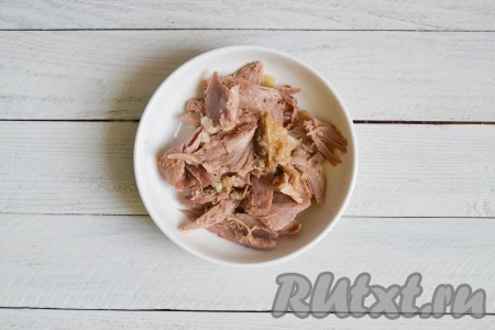 Подготовить лоточки для холодца или обычные тарелки для первых блюд. Разложить в них мясо и, по желанию, добавить измельченный прессом чеснок.
