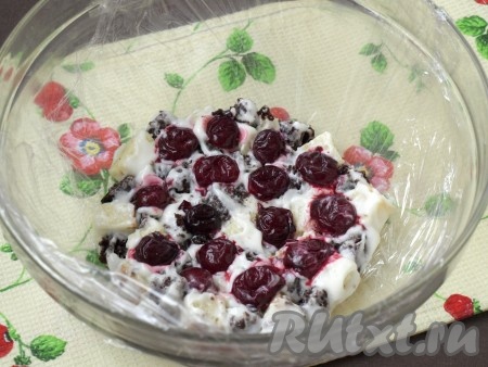 Для сборки торта "Панчо" нужно использовать подходящую ёмкость, например, салатник. Застелить его пищевой плёнкой. На дно посуды первым слоем выложить кусочки бисквита, чередуя светлые и тёмные кусочки, которые предварительно окунули в сметанный крем. Сверху выложить вишню.