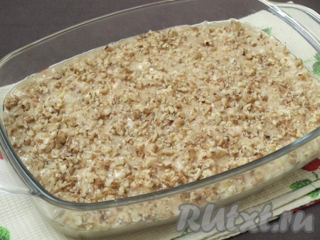 Форму для выпечки (у меня размер формы 17 на 25 см) смазать растительным маслом, выложить тесто и разровнять лопаткой. Сверху посыпать оставшейся частью орехов.