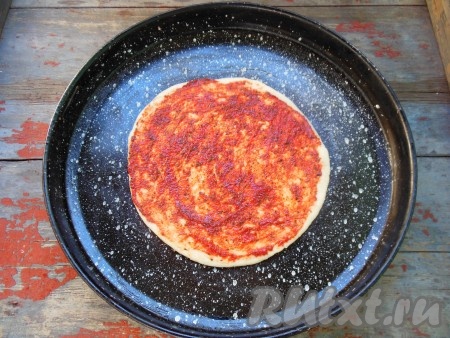 Растяните тесто при помощи ладошек. Смажьте тесто томатным соусом, либо кетчупом.