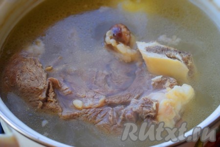 Говядину целым куском выкладываем в кастрюлю, полностью заливаем водой, для аромата добавляем 1 очищенную луковицу, ставим на огонь, после закипания уменьшаем огонь, снимаем пену и варим мясо до готовности (в течение 2-3 часов). Когда говядина сварится, луковицу вынимаем из бульона (она нам больше не понадобится).
