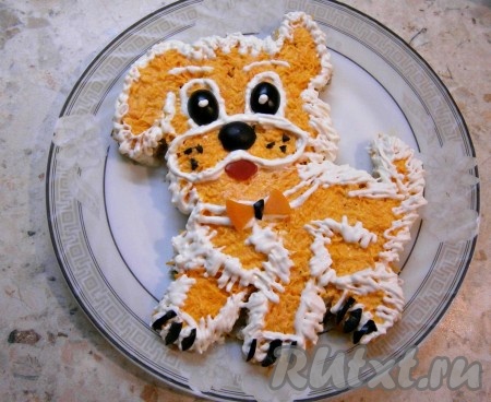 Теперь нужно проявить небольшие навыки художника и сметаной нарисовать мордочку, бровки, глазки и сделать окантовку в некоторых местах зигзагами, имитируя шерстку. Зрачки и носик сделать из половинок черных маслин, из маленьких кусочков маслин - усики и коготки на лапках, язычок (ротик) сделать из кусочка свежего помидора. Бантик на ошейнике - это кусочки вареной моркови.
