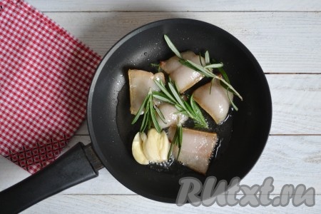 Через минуту, когда появится вытопившейся жир, выложить в сковороду очищенные зубчики чеснока и веточки розмарина. Свежий розмарин можно заменить сухим или другими ароматными травами.
