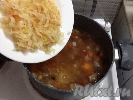 По истечении времени квашеную капусту слегка отжимаем от лишней жидкости и добавляем в кастрюлю.