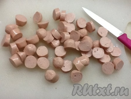 Нарезаем сосиски и отправляем вслед за квашеной капустой и томатом.