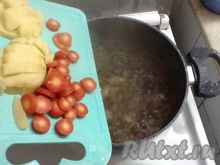 Когда лук обжарится до золотистого цвета, добавляем в кастрюлю горячую кипячёную воду и высыпаем туда картошку с морковкой, подсаливаем и варим на среднем огне, примерно, 10 минут. 