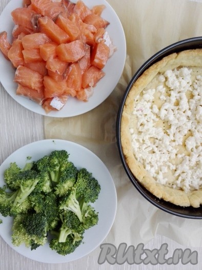 На выпеченную основу киша выложить сыр, распределить кусочки красной рыбы и брокколи, слегка посыпать солью и молотым черным перцем.
