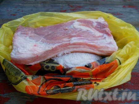 Сало промойте проточной водой, хорошо зачистите ножом со всех сторон, а затем обсушите при помощи бумажного полотенца. На дно пакета насыпьте соль, затем положите сало.