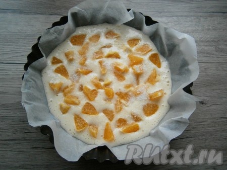 Тесто получится похожим на сметану или крем. Форму диаметром 18-20 см застелить пергаментом. Вылить половину теста, разровнять. Выложить кусочки апельсинов. Если они кисловатые - посыпать немного сахаром.