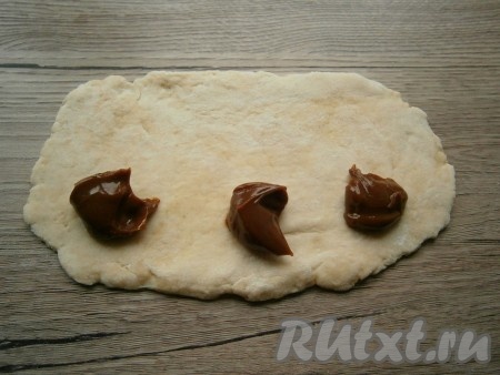 На один край каждой раскатанной части теста выложить по 0,5 чайной ложки вареного сгущенного молока или другой начинки (я из каждой раскатанной части теста решила сделать по 3 печенья, поэтому выложила 3 раза по половине чайной ложки начинки).
