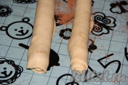 Свернуть каждую часть теста с начинкой в тугой рулет. В результате получится 2 рулета, которые и станут рождественскими венками.
