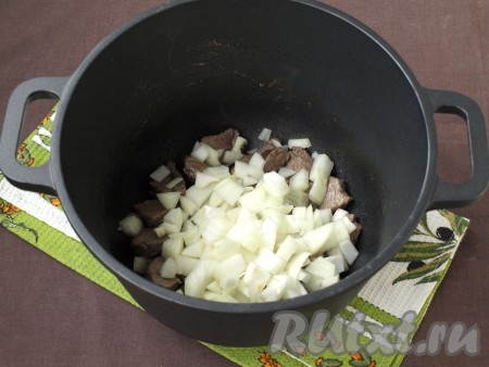 Разогреть в казане (или толстостенной кастрюле) растительное масло, добавить в него мясо и обжарить на среднем огне со всех сторон до румяности. Затем добавить лук и готовить около 3-х минут, иногда перемешивая.
