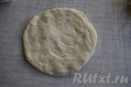 Берем кусочек теста и слегка раскатываем на столе, присыпанном мукой.
