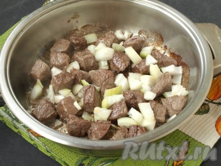 Разогреть в сковороде подсолнечное масло, выложить кусочки мяса и обжарить на среднем огне до румяной корочки со всех сторон. Затем выложить к мясу нарезанный кубиками очищенный лук и обжарить, помешивая, до прозрачности лука.