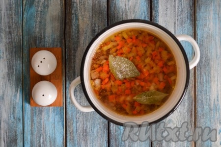 Выложить в кастрюлю обжаренные овощи, лавровые листики и щепотку соли (не пересолите, так как тушенка бывает достаточно соленой).
