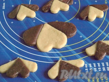 Затем половину сердечек нужно будет разрезать пополам. Целые сердечки – это мордочки, а половинки – уши собачек. Там где мордочка светлая, делаем тёмные ушки и наоборот, где мордочка тёмная – уши светлые. Если у вас есть формочки разного размера, можно сделать печенье разной величины.
