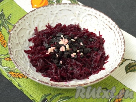 Взять третью тарелку, натереть в неё очищенную варёную свеклу, добавить к ней нарезанный кубиками чернослив и 1 измельчённый зубчик чеснока, посолить, поперчить и перемешать.