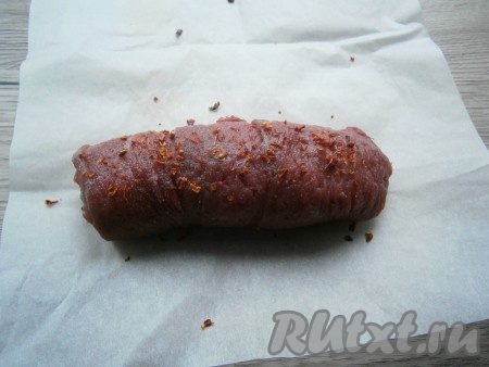 Поместить рулет из говядины с начинкой на лист пергамента, мясо сверху немного посолить, посыпать специями и паприкой.