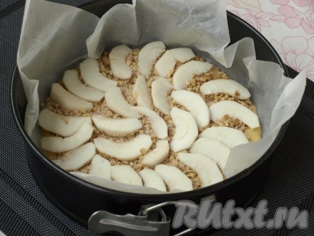 Форму диаметром 22 см застелить пергаментом, вылить половину теста. Посыпать половиной ореховой смеси. Яблоки очистить и нарезать тонкими пластинами. Половину яблок разложить сверху орехового слоя. Здесь яблоки советуют присыпать крахмалом. Я этот шаг пропустила, так как яблоки у меня были твёрдые и я решила, что посыпать их не стоит.