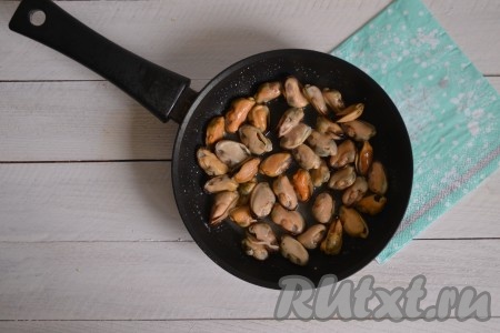 Жарить замороженные мидии на среднем огне, периодически помешивая. С первых же секунд в сковороде появится много жидкости.
