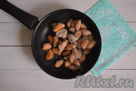 Сразу же в сковороду выложить замороженные очищенные мидии.
