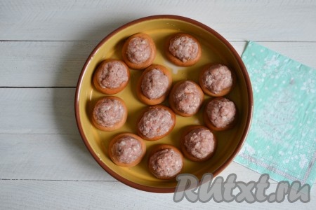 Баранки вынуть из молока и выложить в форму для запекания. Ладошками скатать из фарша мясные шарики и выложить сверху на баранки, немного вдавливая в серединку, как на фото.
