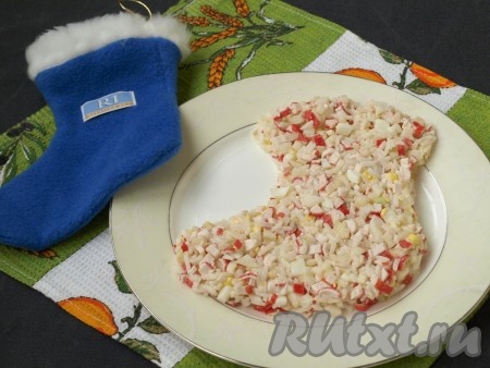 На плоскую тарелку выложить салат в виде сапожка. Можно заранее сделать шаблон из бумаги или, как образец, положить рядом сапожок из ткани.