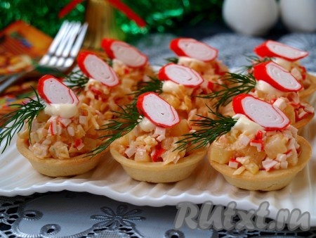 Полученной массой наполнить тарталетки, украсить по своему желанию (я украсила зеленью и кусочками крабовых палочек). Подать вкуснейшие тарталетки с крабовыми палочками, сыром и ананасами к праздничному столу.
