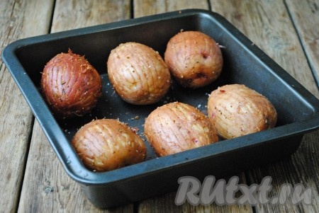 Затем тщательно руками втереть в картошку соль, чёрный молотый перец и приправу для картофеля. Выложить картофель в подходящую жаропрочную форму. Лучше всего, чтобы форма была металлической, в ней в процессе запекания на поверхности картошки получается наиболее румяная и хрустящая корочка. 