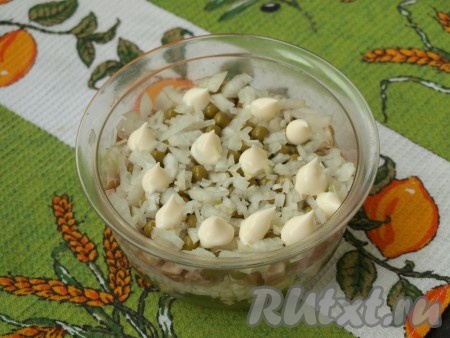 Далее выложить равномерно горошек, следующим слоем разложить очищенный и мелко нарезанный лук.