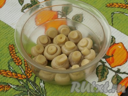 Морковь заранее отварить в кожуре до готовности (в течение минут 30-35 с момента закипания воды). Яйца отварить в течение 10 минут с момента начала кипения воды. Варёные яйца и морковь остудить, очистить. Для формирования салата "Грибная поляна" я использую глубокий контейнер круглой формы из пищевого пластика, который не нужно застилать пищевой плёнкой, в нём салат не прилипает к стенкам и без проблем выходит из формы. Но я советую всё же форму для формирования салата застелить пищевой плёнкой так, чтобы края плёнки свисали с краёв формы. На дно формы выложить маринованные шампиньоны шляпками вниз.