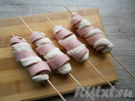 Каждую часть теста скатать в жгутик и обмотать им по разрезам каждую сосиску.