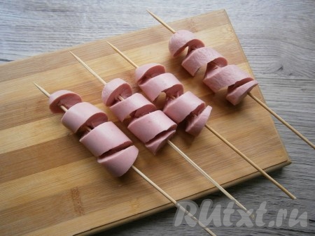 Затем сосиски, нарезанные спиралькой, немного растянуть.
