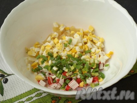 Варёные яйца очистить и также измельчить кубиками. Нашинковать зелёный лук. Лук и яйца выложить в салат из крабовых палочек и ананасов.
