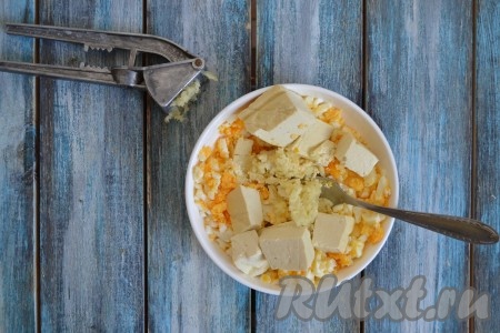 К яйцам и сыру добавить чеснок, пропущенный через пресс.
